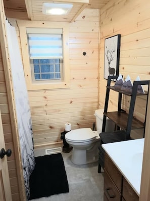 A small, wooden cabin bathroom with a toilet, sink, and a window. - Queen of Hearts. Secluded Hocking Hills cabin. (Rockbridge)