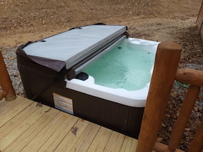 A hot tub with a wooden deck and a metal cover. - Queen of Hearts. Secluded Hocking Hills cabin. (Rockbridge)