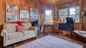 A cozy cabin interior with a wooden interior, a sofa, a desk, and various informational posters on the walls. - 4 Lovely Suite near Acadia Open Hearth Inn (Trenton)
