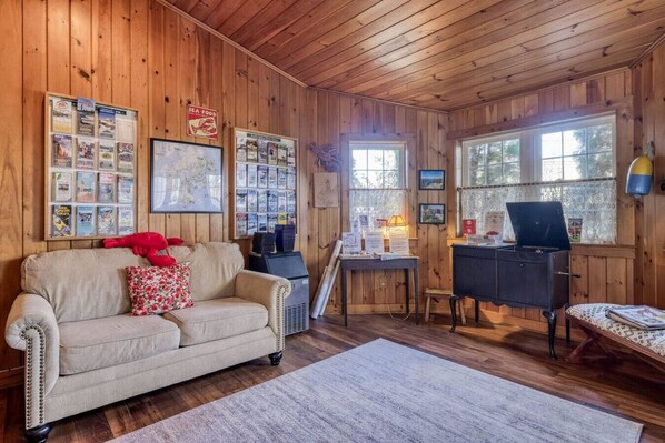 A cozy cabin interior with a wooden interior, a sofa, a desk, and various informational posters on the walls. - 4 Lovely Suite near Acadia Open Hearth Inn (Trenton)