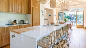 A modern kitchen with a central island, wooden cabinets, and hanging wicker pendant lights.