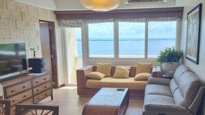 Un salon avec un canapé, une télévision et une vue sur la mer.
