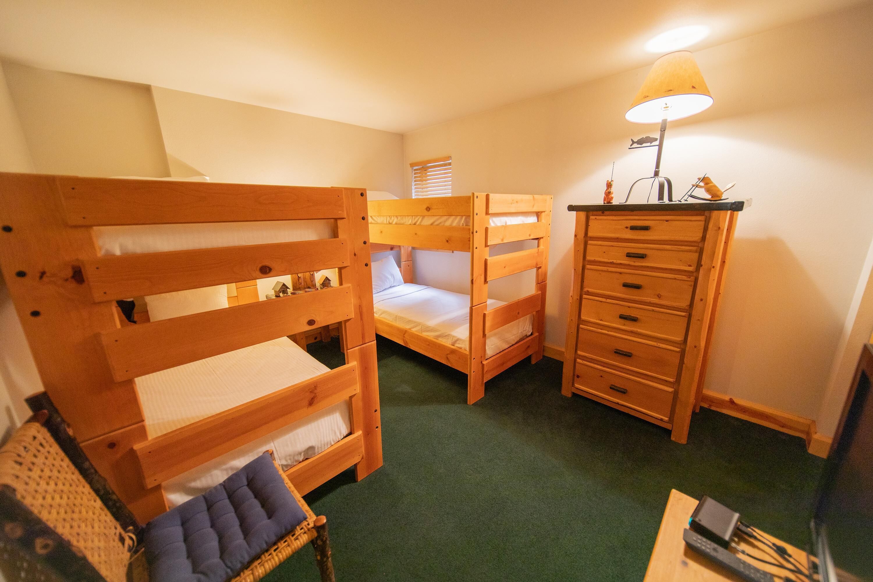 Une chambre avec des lits superposés, une commode, une lampe et un téléviseur.