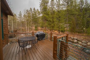 A wooden deck with a table and chairs, surrounded by a wooden fence and a view of a forest. - Starfire 1972 (Keystone)