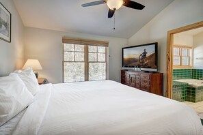 A bedroom with a bed, a television, a ceiling fan, a window, and a bathroom with a bathtub. - Starfire 1972 (Keystone)