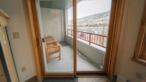 Quarto com porta de vidro deslizante que dá para uma varanda com vista para uma paisagem coberta de neve.