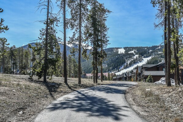A road leading to a mountain lodge with a clear view of the surrounding forest and mountains. - Gateway Lodge 5024 (Keystone)