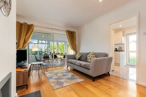 Ein modernes Wohnzimmer mit Sofa, Fernseher und Essbereich.