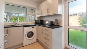 A modern kitchen with a washing machine, microwave, and toaster. - Ty Gwyn - Hot Tub Parking Dog Friendly (Saundersfoot)
