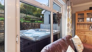 Une pièce dotée d’une porte vitrée donnant sur un jardin, d’un jacuzzi et d’un meuble en bois orné d’un objet décoratif.