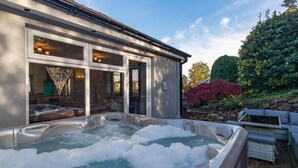 Un bain à remous avec vue sur un immeuble aux grandes fenêtres et un jardin où poussent différentes espèces de plantes.