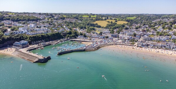 Vue aérienne d’une ville côtière avec un port de plaisance, une plage de sable et des quartiers résidentiels.