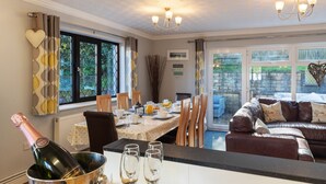 Un coin repas avec une table dressée pour quatre personnes, une bouteille de champagne et deux verres.