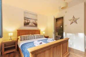 Une chambre avec un lit en bois, deux tables de chevet avec des lampes, un tableau au mur et une décoration en forme d’étoile.