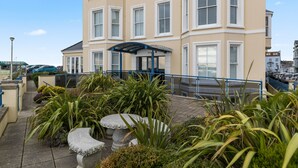 A multi-story hotel with a covered entrance, outdoor seating area, and a parking lot.