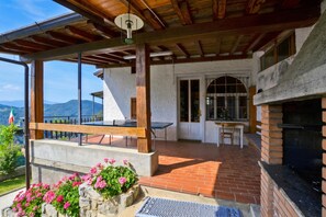 A covered patio with a table and chairs, a brick fireplace, and a view of the mountains.