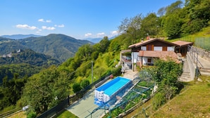 Uma casa com piscina, rodeada por vegetação exuberante e montanhas.