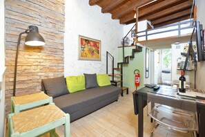 Una sala de estar acogedora con un sofá, una lámpara, un cuadro y una escalera.