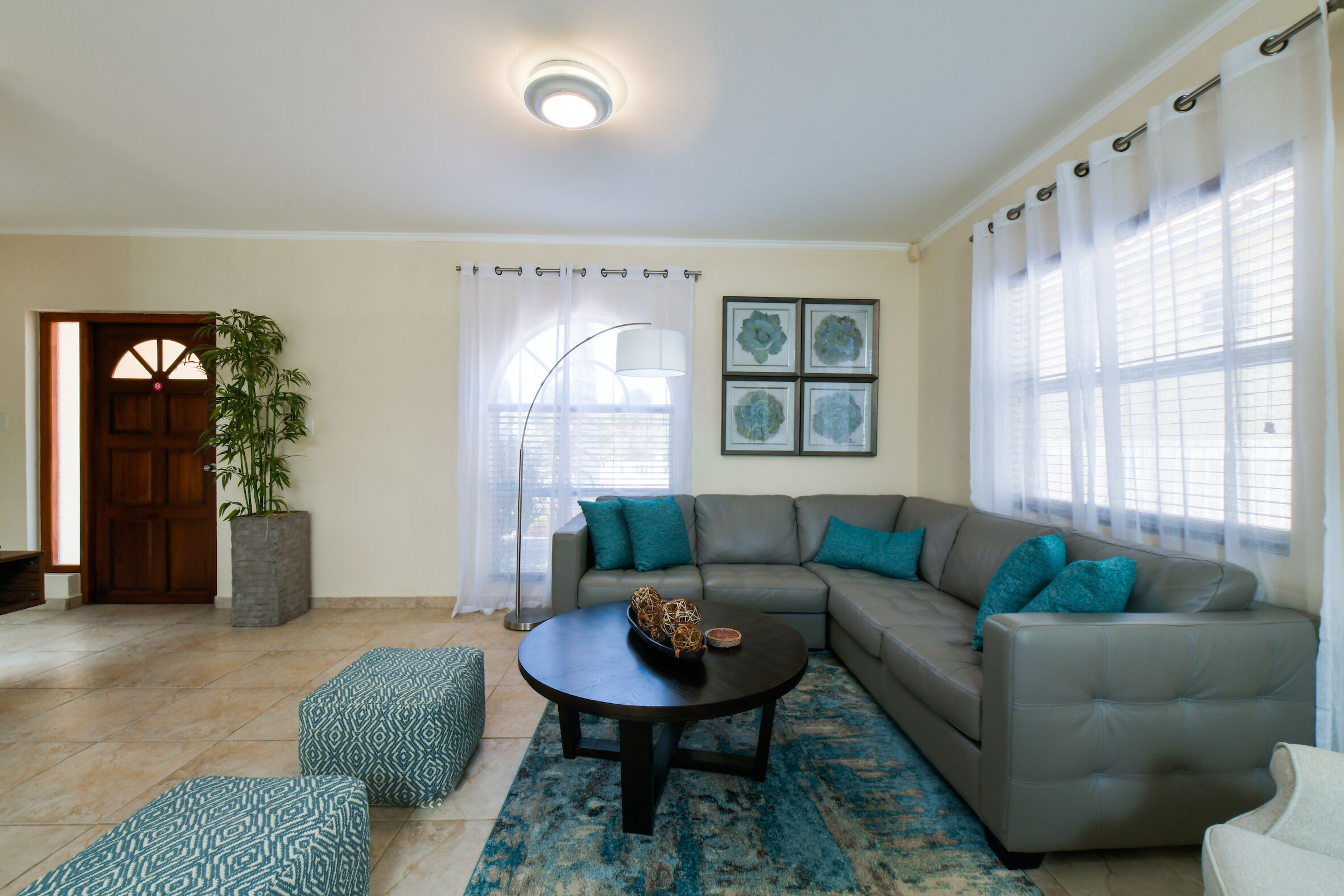 Una sala de estar con un sofá modular, una mesa de centro redonda y un ventanal con cortinas traslúcidas.