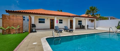 A swimming pool with lounge chairs and a covered patio area.