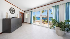 Amplia habitación con un amplio ventanal corredero que da a un balcón con vistas al océano y palmeras.