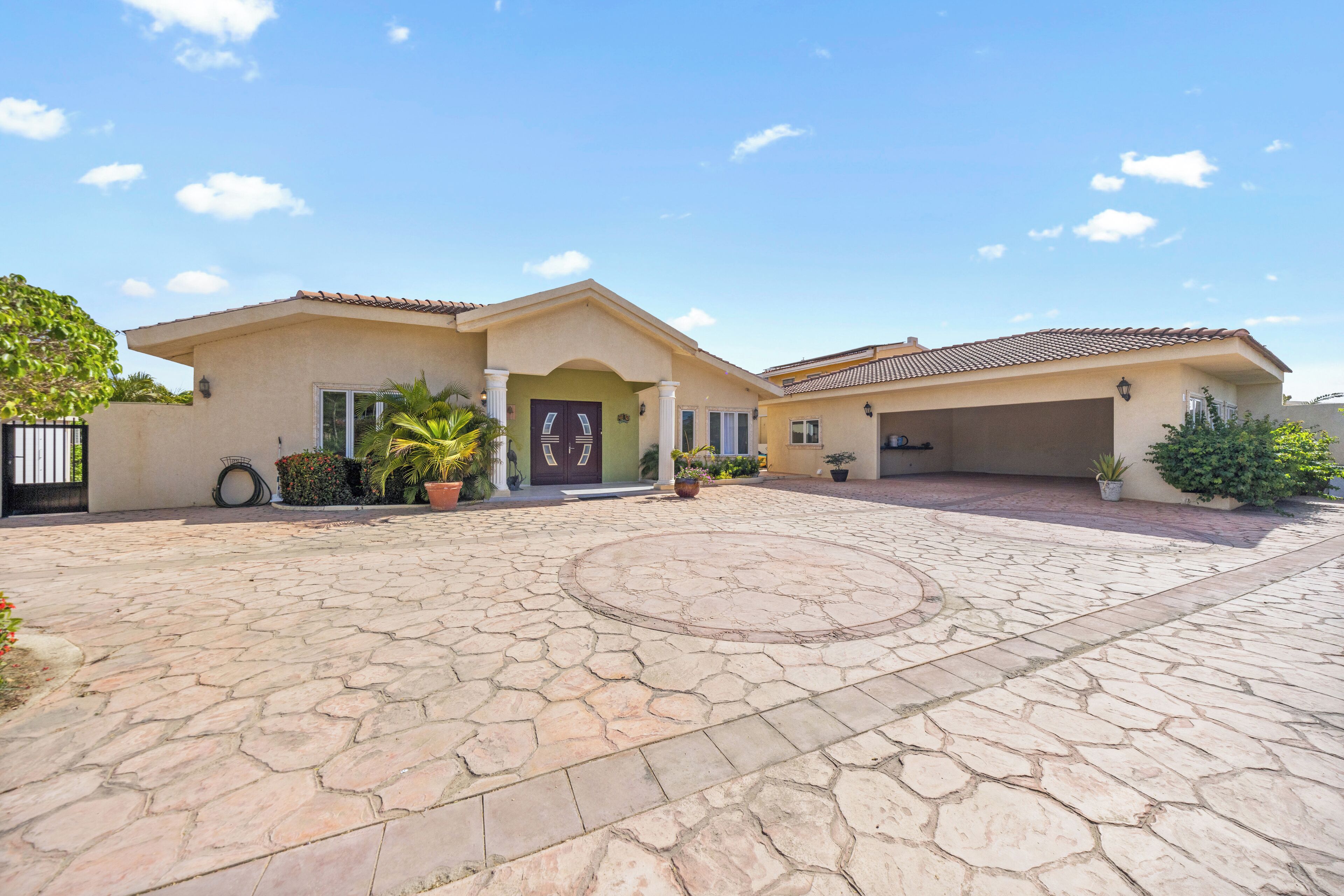 A two-story house with a paved driveway and a circular stone pattern in the center.