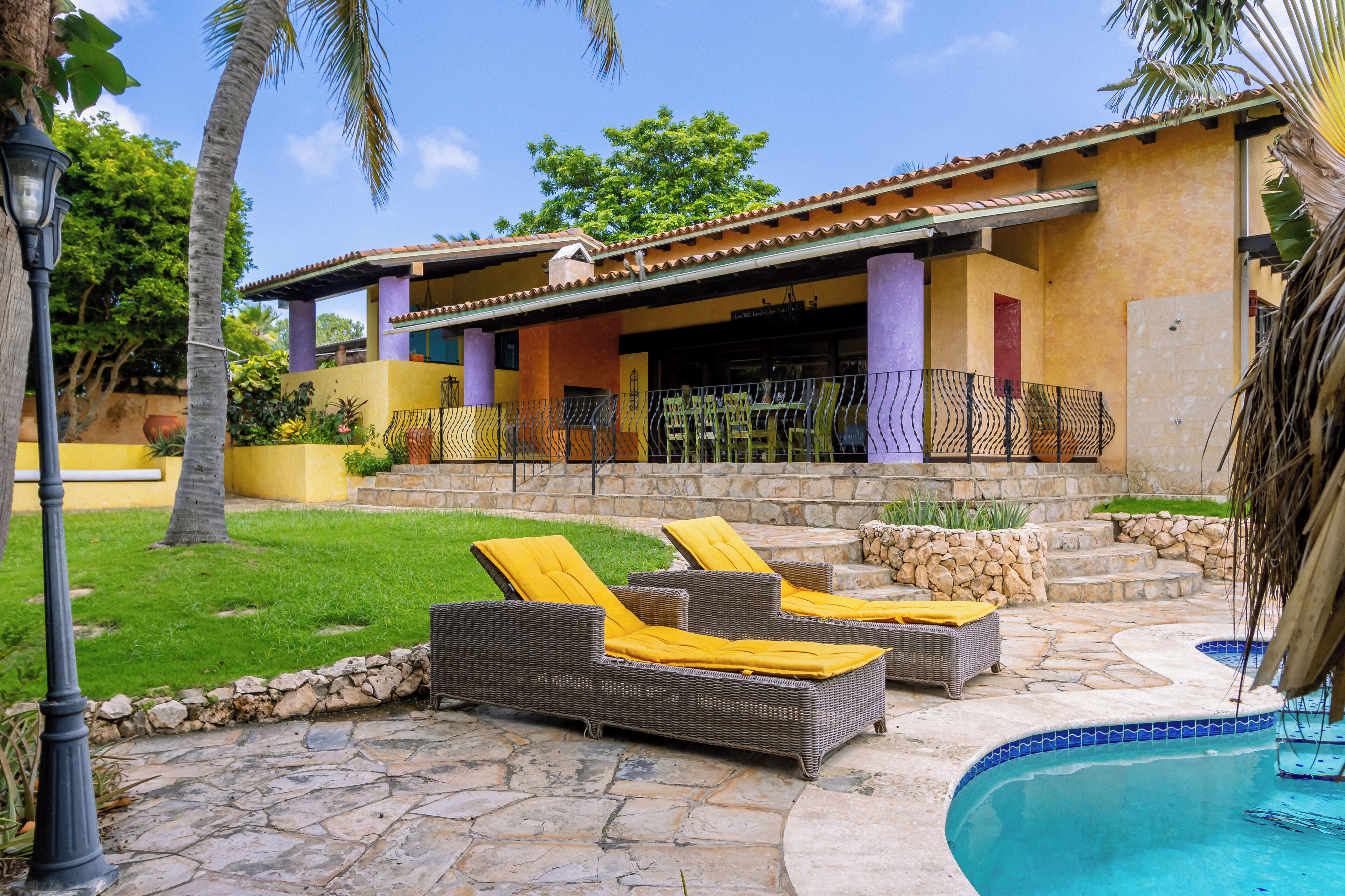 A poolside area with wicker lounge chairs and a stone patio.