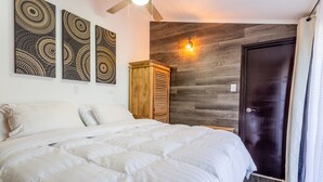 Un dormitorio con una cama grande, un armario de madera y tres cuadros en la pared.