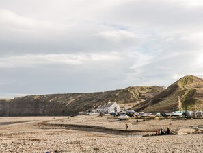 A coastal area with a white building, boats, and a rocky beach.