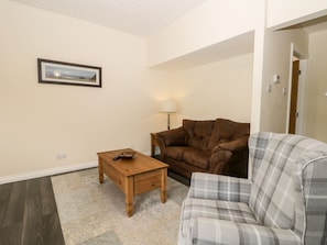 A living room with a brown leather couch, a plaid sofa, a wooden coffee table, and a framed picture on the wall.