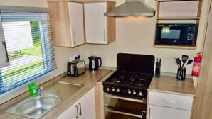 Une cuisine compacte équipée d’une cuisinière à gaz, d’un four à micro-ondes, d’un grille-pain et d’un évier.