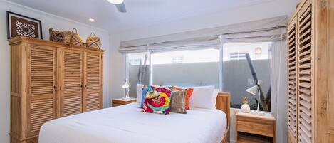 A bedroom with a large bed, wooden wardrobe, and a ceiling fan.