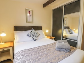 A neatly made bed with a patterned bedspread, a pillow, and two bedside lamps.