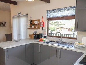 A kitchen with a sink, a fire blanket, and a window with a view of the outside. - Bugle (Saltburn-by-the-Sea)
