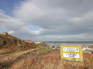 A coastal road sign indicating Saltburn by the sea and a request to please drive slowly.