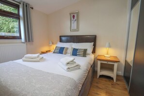 A neatly made bed with a patterned bedspread, two bedside tables with lamps, and a framed picture on the wall. - Bugle (Saltburn-by-the-Sea)