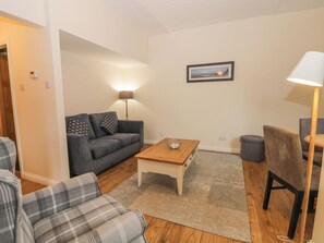 A living room with a sofa, a coffee table, a lamp, and a chair. - Bugle (Saltburn-by-the-Sea)