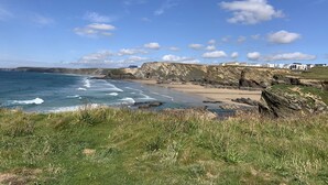A coastal landscape with a beach, cliffs, and a clear sky.