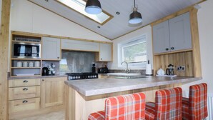 A modern kitchen with wooden cabinets, a central island with bar stools, a microwave, and a gas stove.