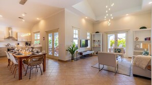 A spacious living area with a dining table, chairs, a sofa, and a TV. - Luxury Pool Villa With View! Cabana, Bbq, 3min/beach, in Tierra del Sol! (Noord)