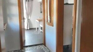 Käytävä, jossa on laatoitettu lattia, puiset ovet ja taustalla näkyy osa ruokailutilasta.
