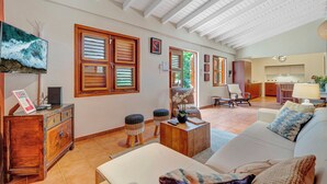 A spacious living area with a high ceiling, wooden furniture, and a view into the kitchen. - Secluded Villa With Pool3min to Beachfree Utilities (Oranjestad)