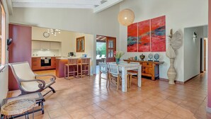 A spacious living area with a dining table, chairs, and a kitchen in the background. - Secluded Villa With Pool3min to Beachfree Utilities (Oranjestad)