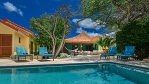 A swimming pool with lounge chairs, a hammock, and a building with a tiled roof and a door. - Secluded Villa With Pool3min to Beachfree Utilities (Oranjestad)