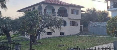 A two-story building with a tiled roof, arched windows, and a gated entrance.