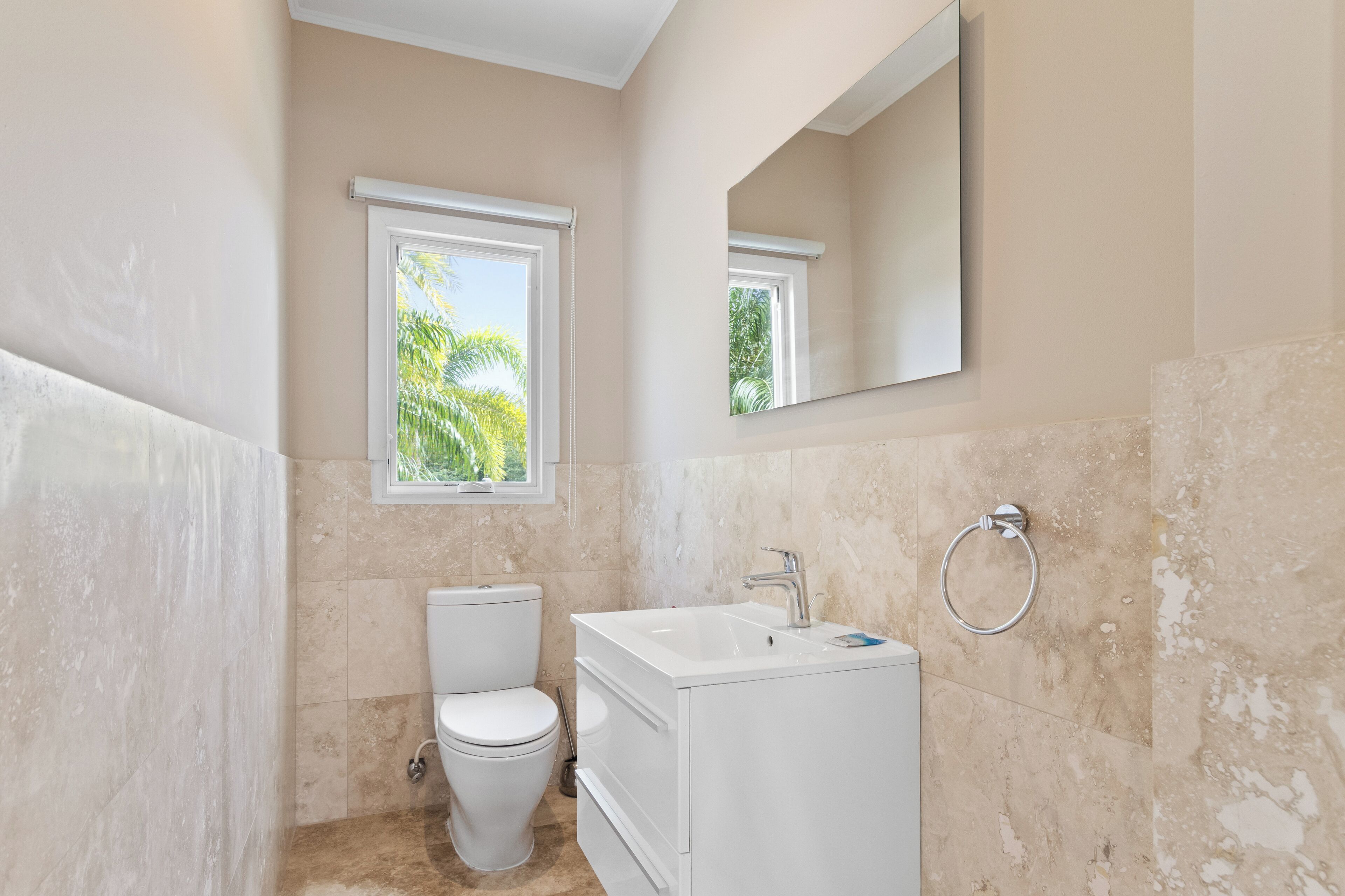 A bathroom with a toilet, sink, and mirror.