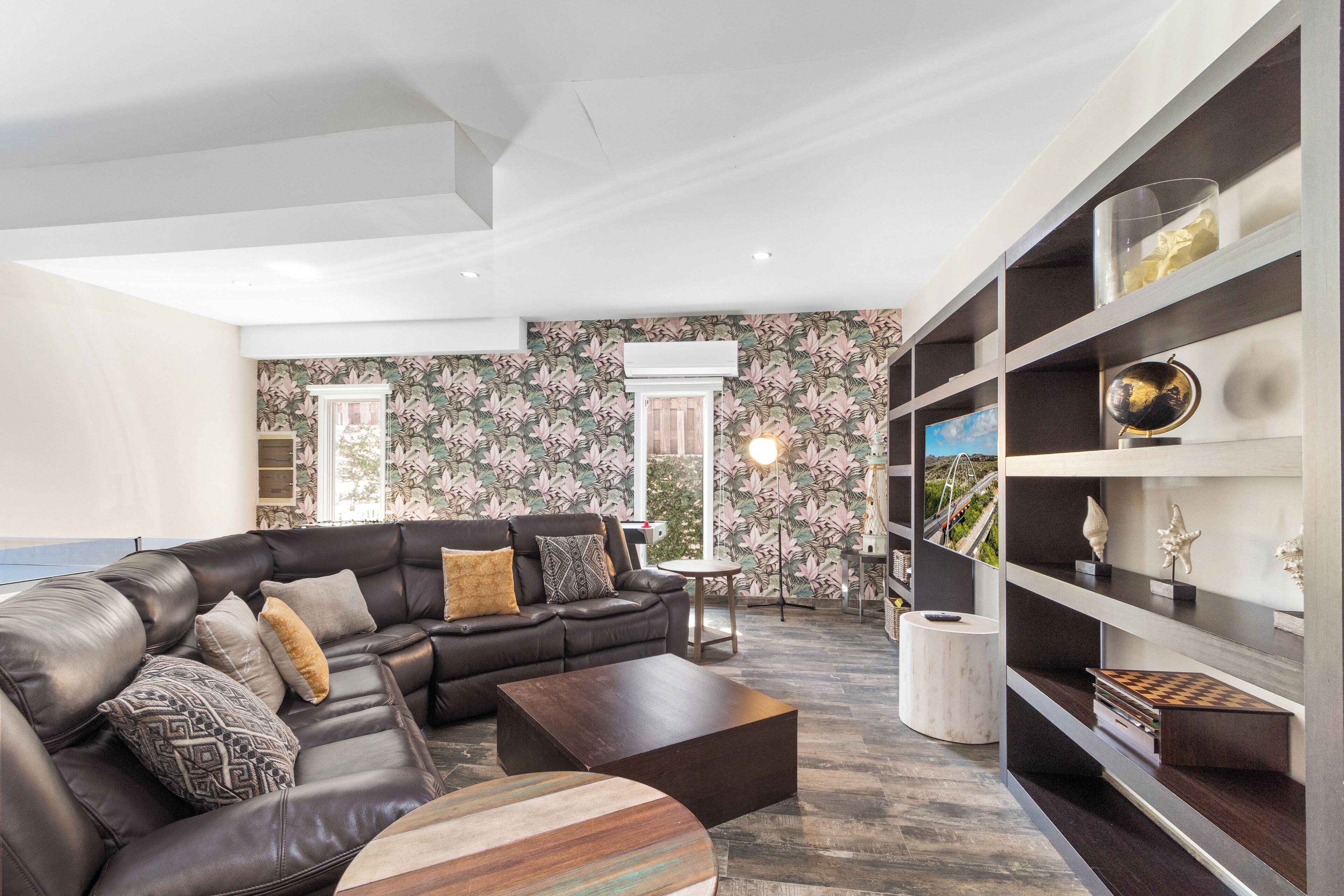 A modern living room with a leather sofa, a coffee table, and a bookshelf.