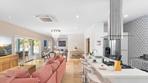 Una cocina moderna con una isla central, electrodomésticos de acero inoxidable y una araña.