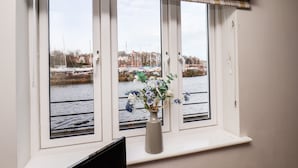 Een raam met een geruit gordijn en een vaas met bloemen op een vensterbank.