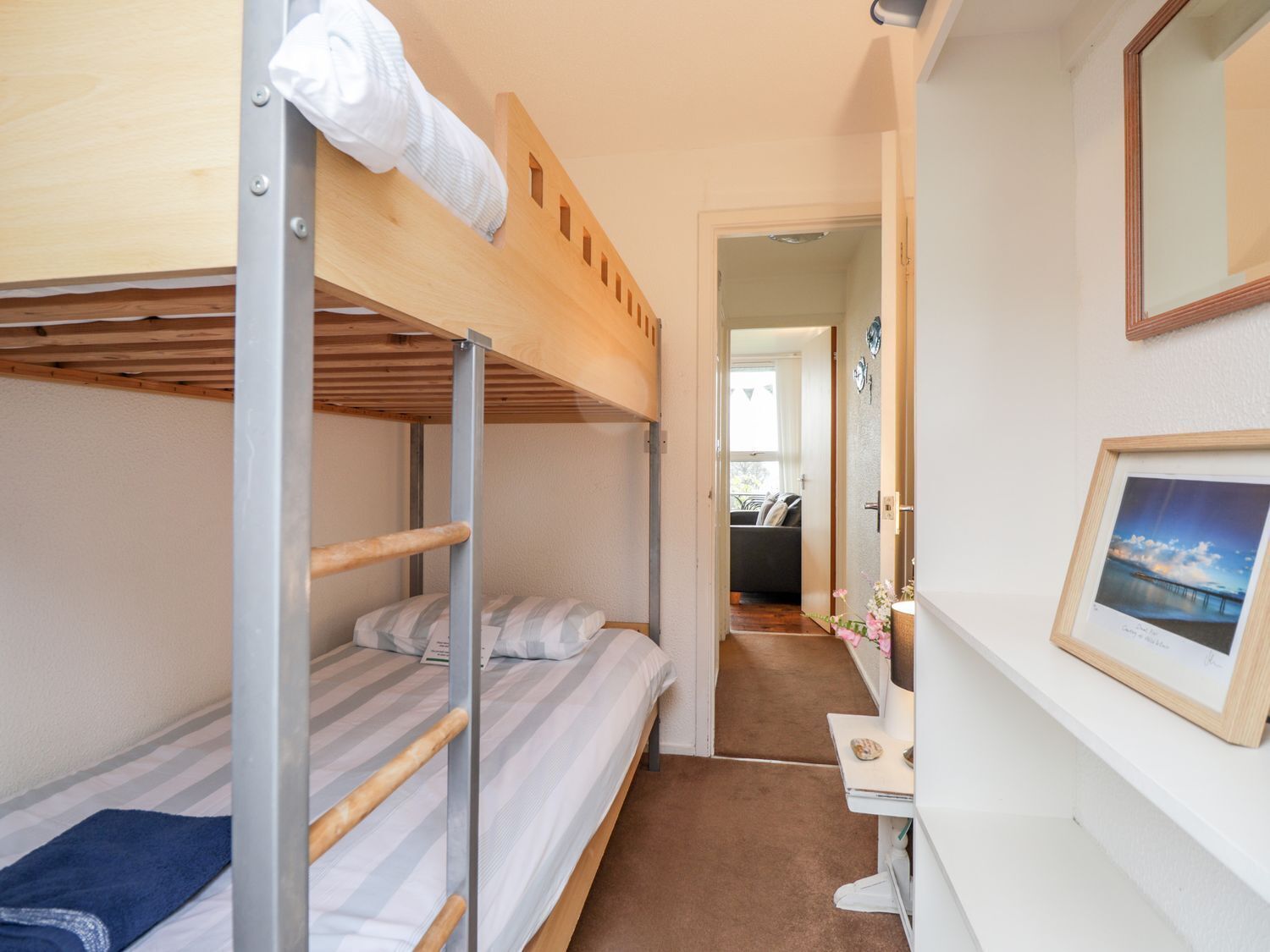 A bunk bed room with a desk and a framed picture on the wall.